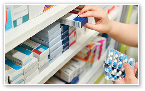 Pharmacist holding medicine box and capsule pack in pharmacy drugstore 